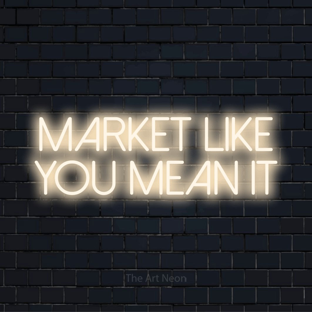 "Market Like You Mean It" script-style LED neon sign on a black brick wall