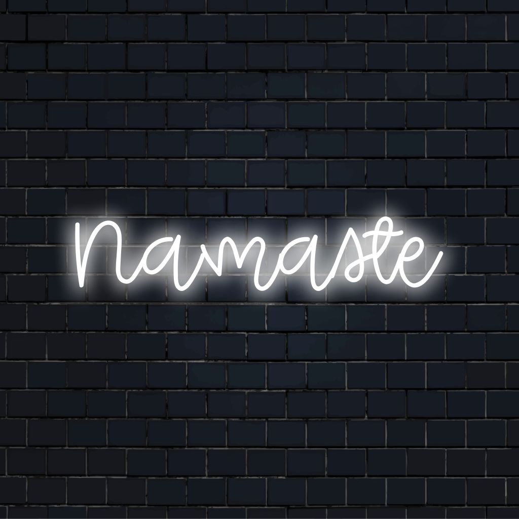 Namaste LED Neon Sign, bright neon lettering against black brick wall