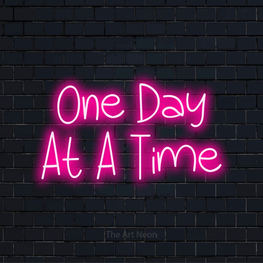 "One Day At A Time" neon text design on a black brick wall