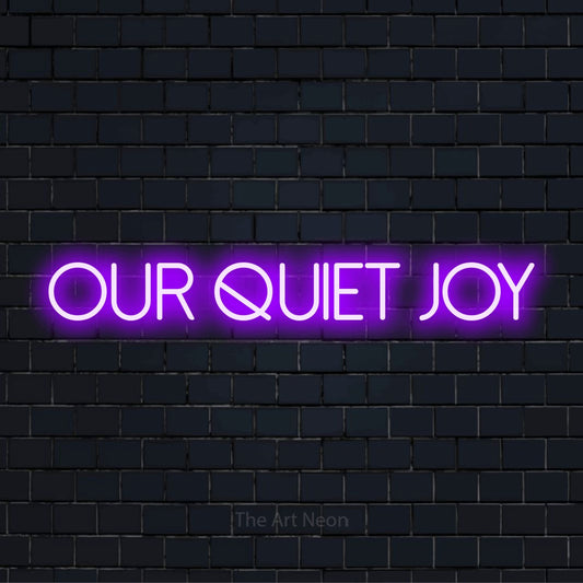 "Our Quiet Joy" glowing LED neon sign on a black brick wall