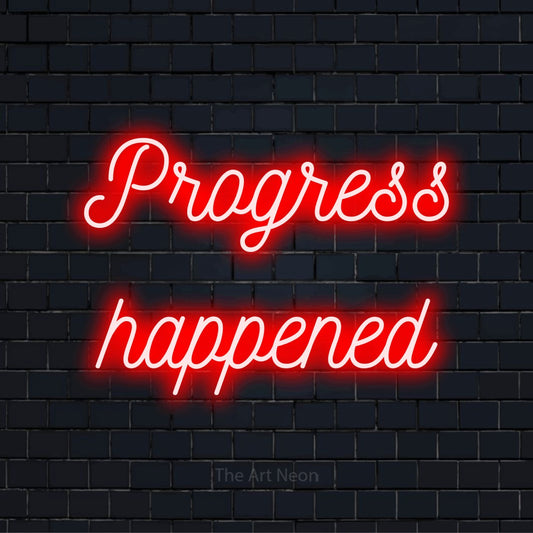 "Progress Happened" script-style LED neon sign on a black brick wall