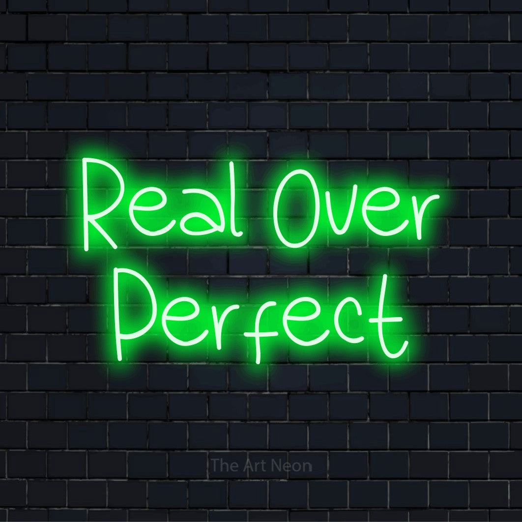 "Real Over Perfect" glowing LED neon sign on a black brick wall