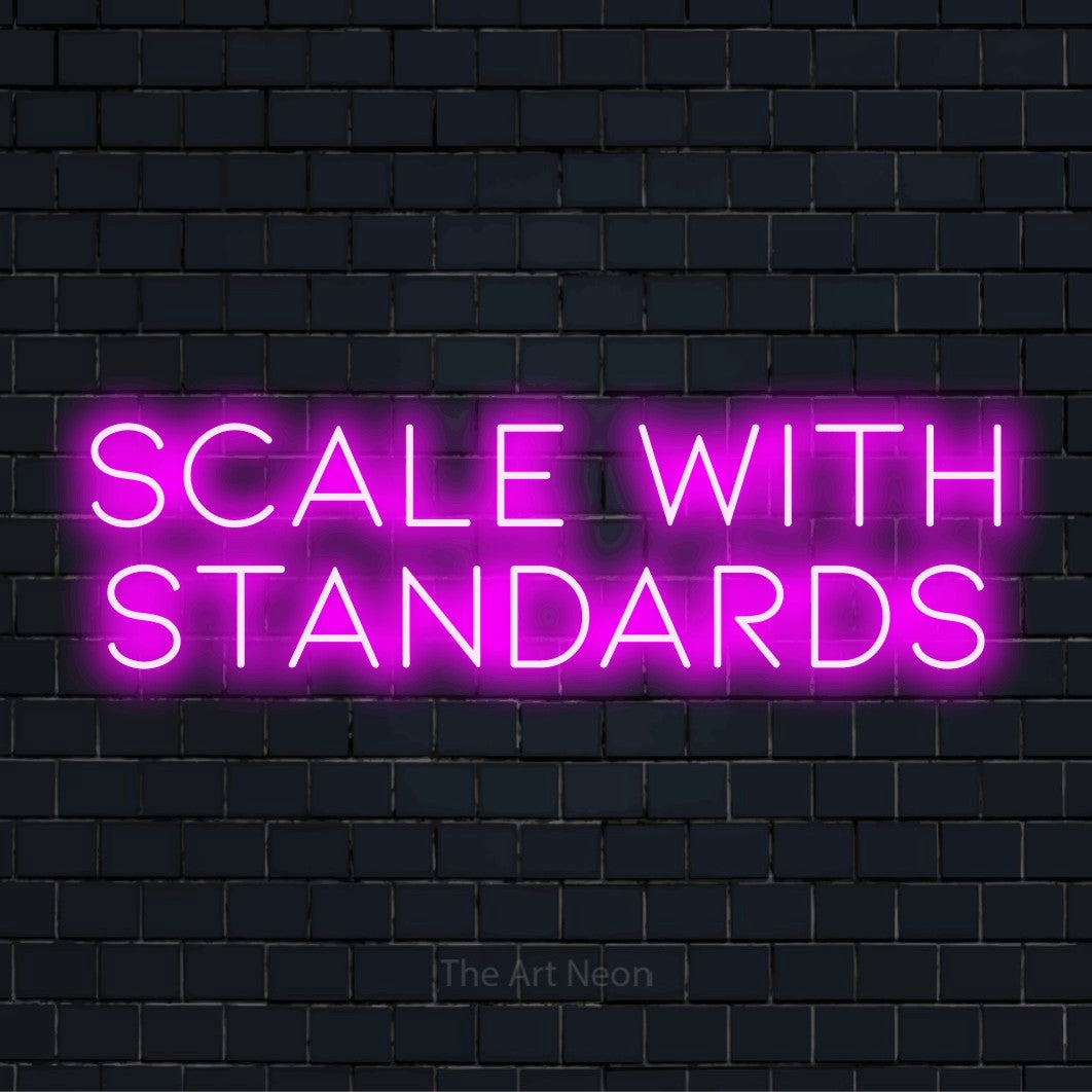 "Scale With Standards" glowing LED neon sign on a black brick wall