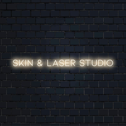 Skin Laser Studio Neon Sign, glowing wall decor against black brick wall