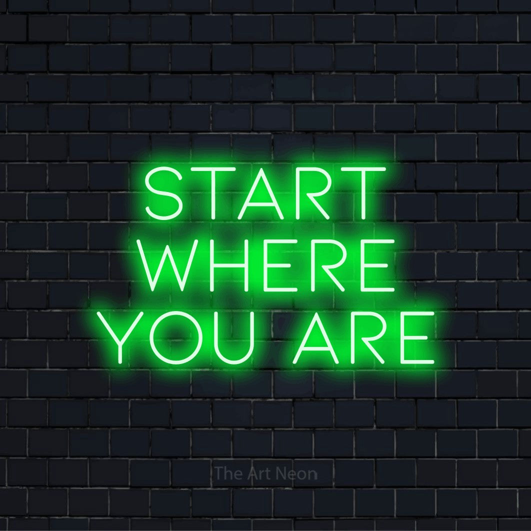 "Start Where You Are" LED neon sign on a black brick wall