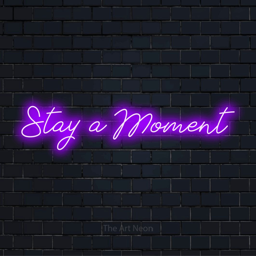 "Stay A Moment" neon text design on a black brick wall