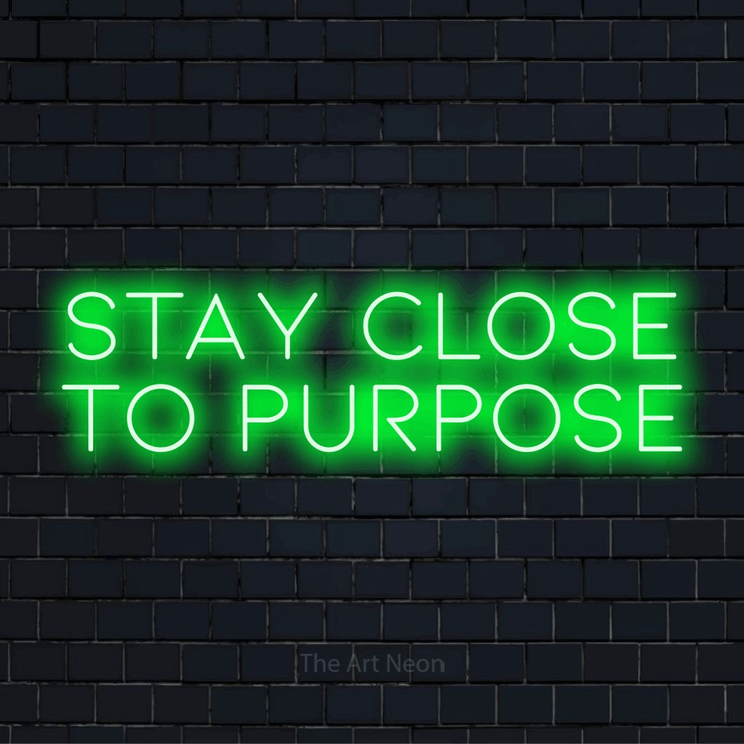 "Stay Close To Purpose" text design with neon effect on a black brick wall