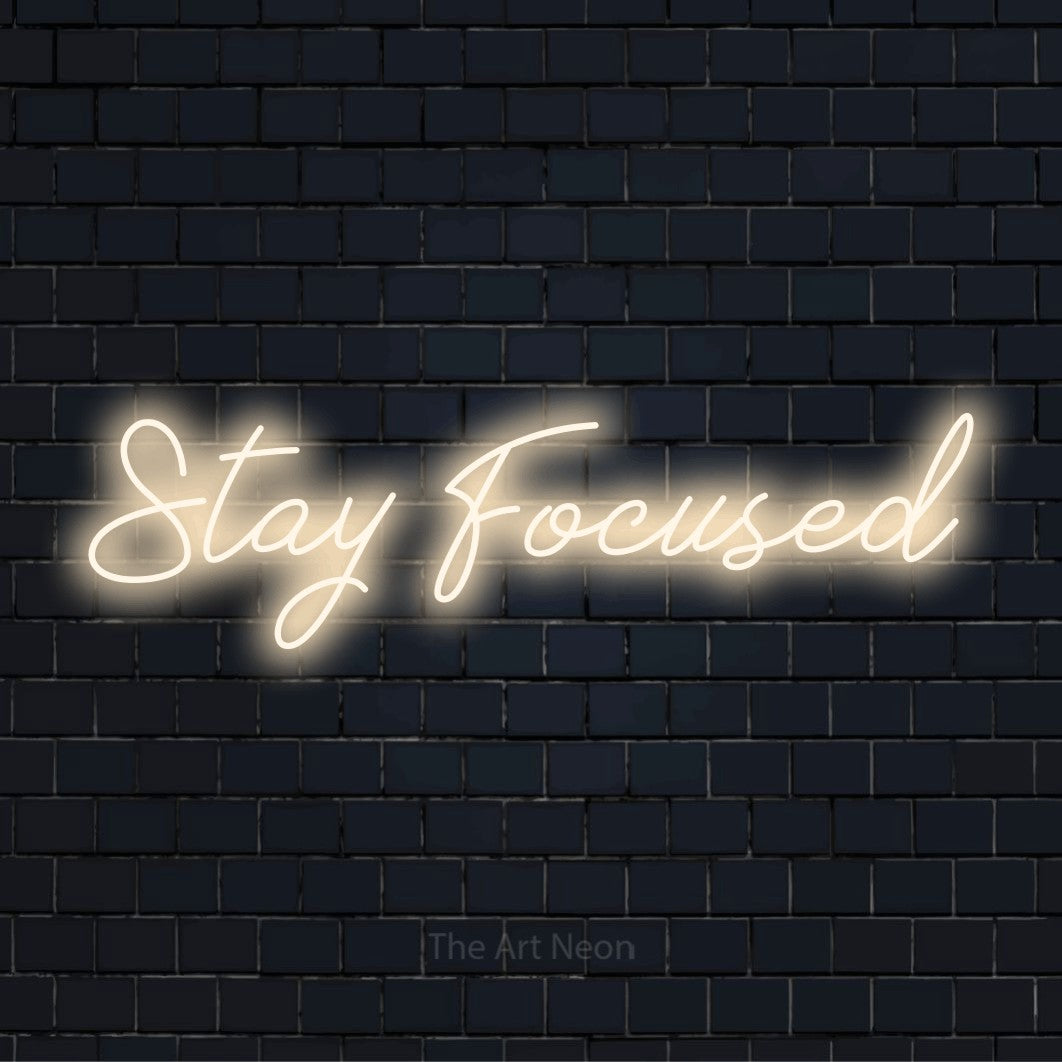 "Stay Focused" text design with neon effect on a black brick wall