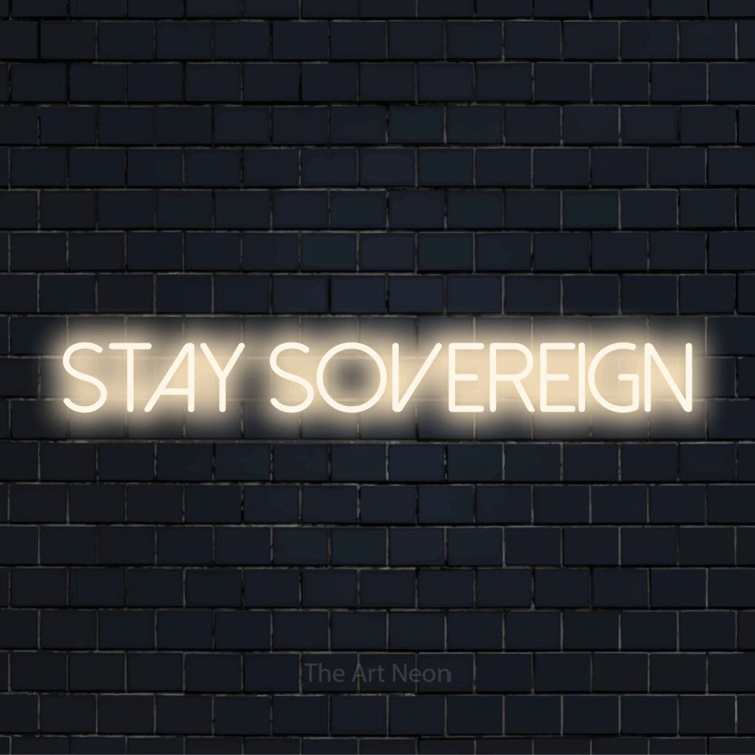 "Stay Sovereign" script-style LED neon sign on a black brick wall