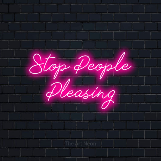 "Stop People Pleasing" script-style LED neon sign on a black brick wall