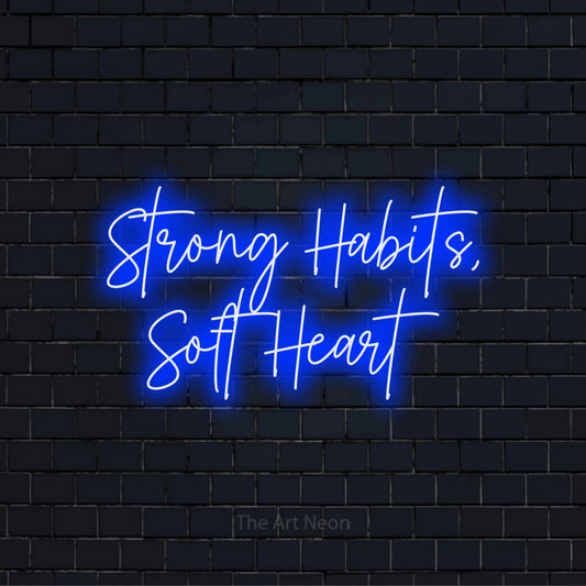 "Strong Habits, Soft Heart" LED neon sign on a black brick wall
