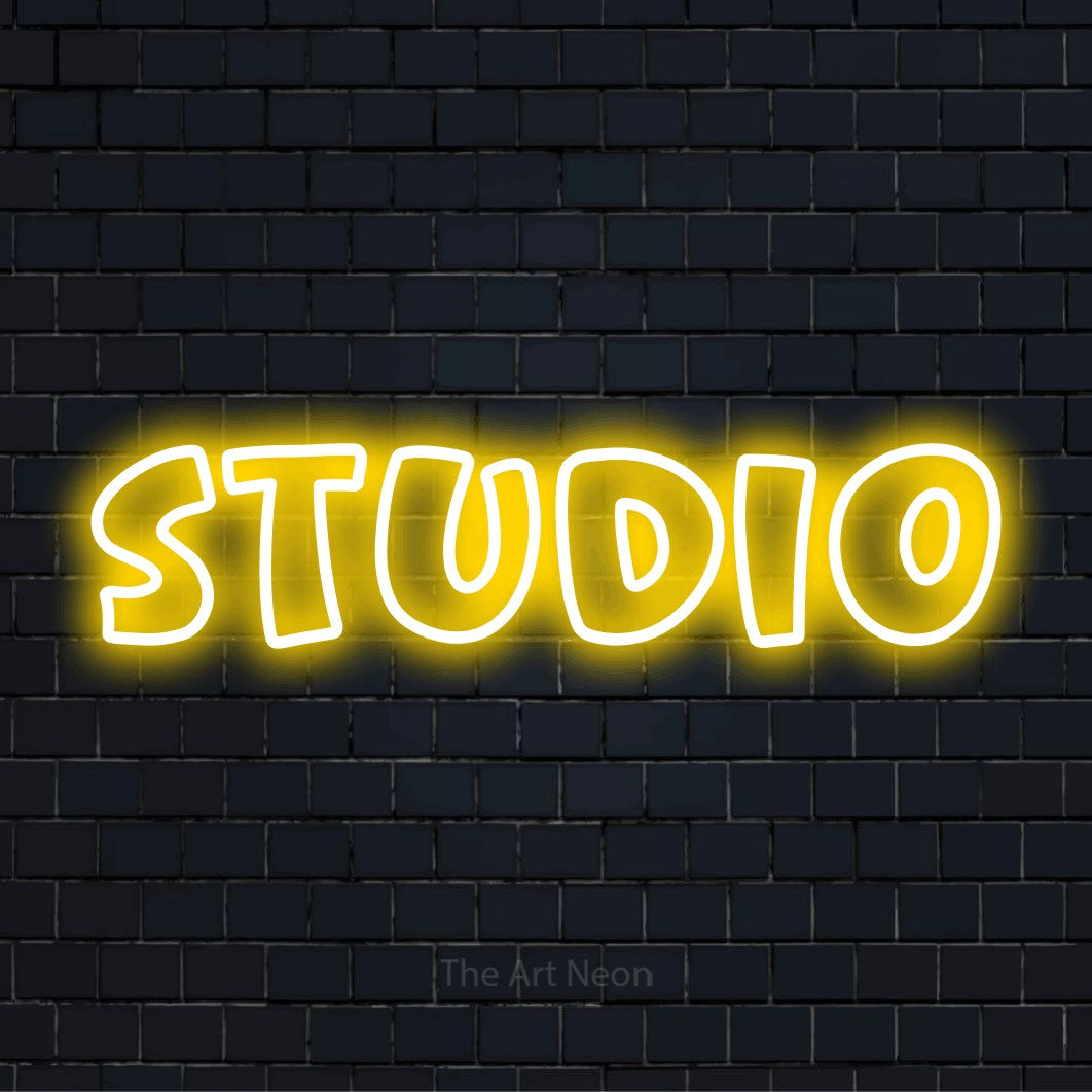 "Studio" glowing LED neon sign on a black brick wall