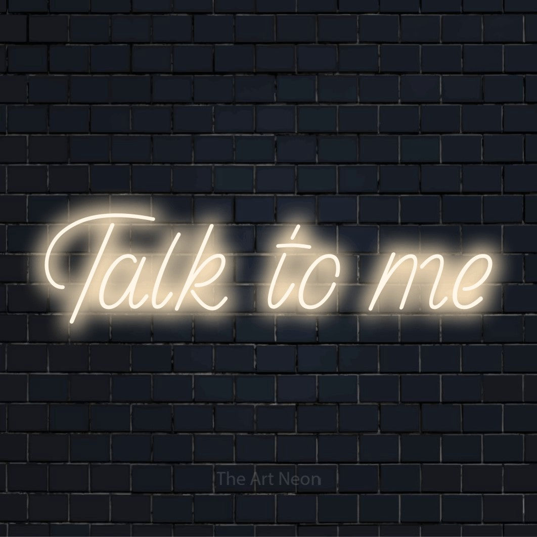 "Talk To Me" glowing LED neon sign on a black brick wall
