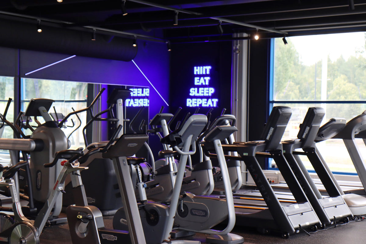 Kuntomaailma gym interior showing a blue LED neon sign at room scale