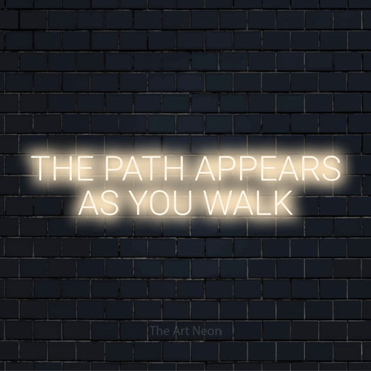 "The Path Appears As You Walk" script-style LED neon sign on a black brick wall