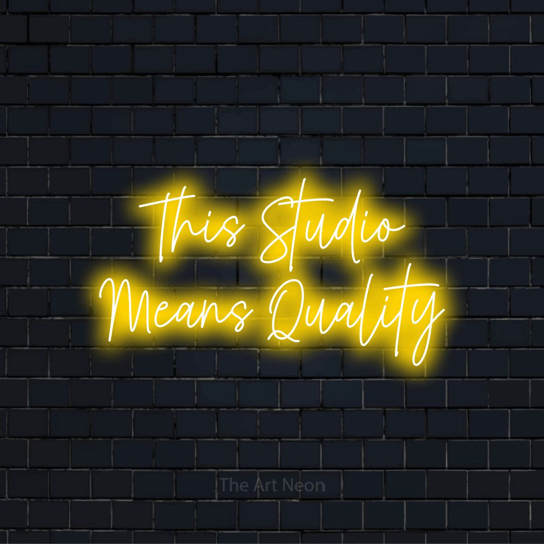 "This Studio Means Quality" script-style LED neon sign on a black brick wall