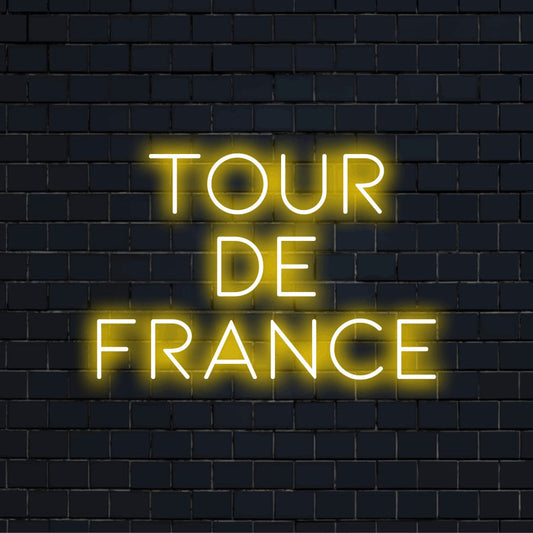 Tour De France Neon Sign, soft neon glow on dark brick wall