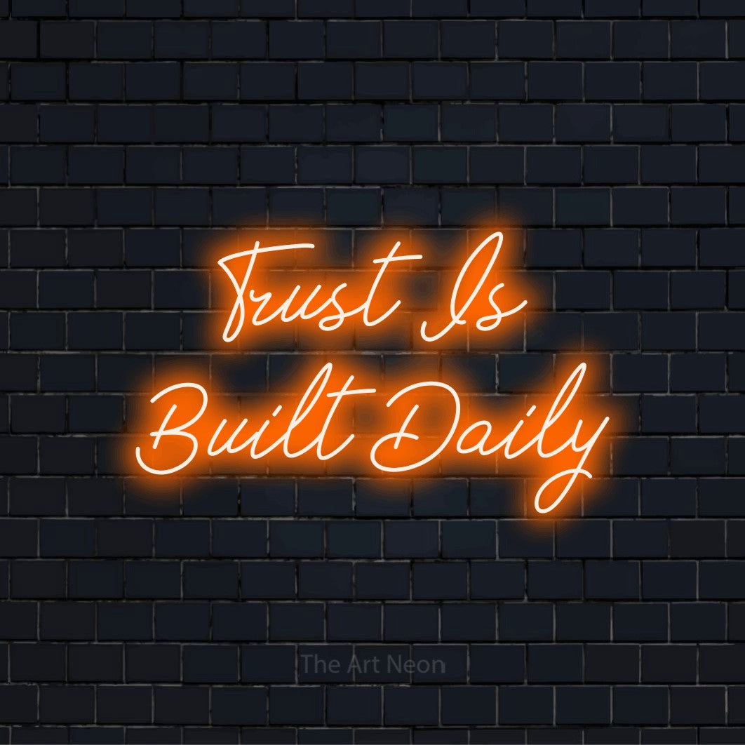 "Trust Is Built Daily" script-style LED neon sign on a black brick wall