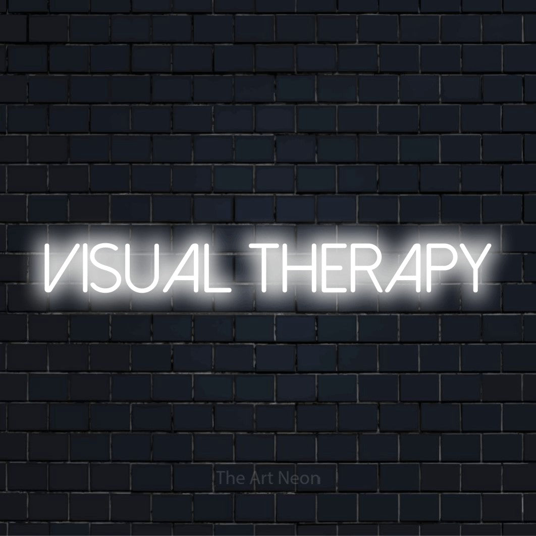 "Visual Therapy" glowing LED neon sign on a black brick wall