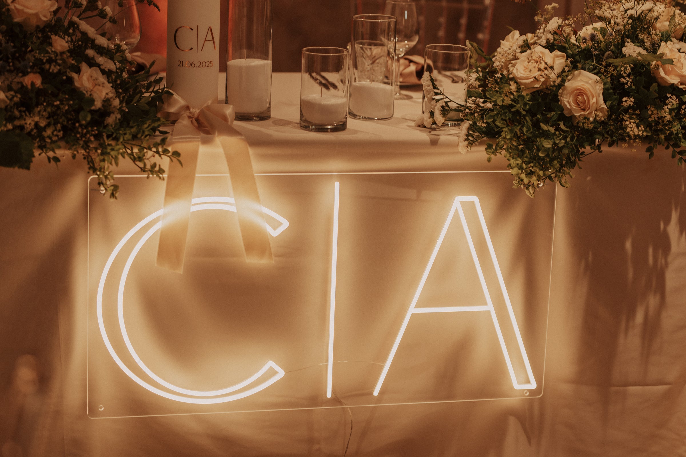 Custom initials LED neon sign glowing above a wedding reception table