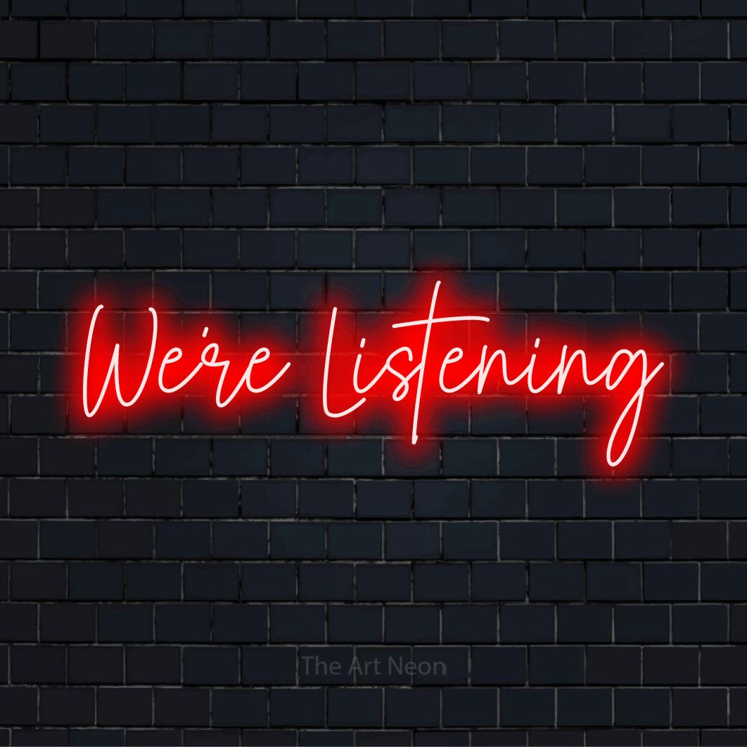 "We’re Listening" script-style LED neon sign on a black brick wall