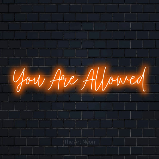 "You Are Allowed" script-style LED neon sign on a black brick wall