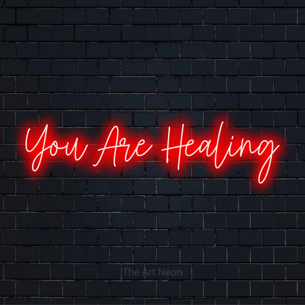 "You Are Healing" LED neon sign on a black brick wall