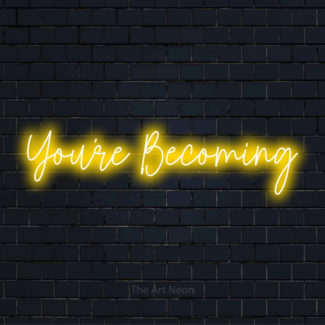"You’re Becoming" glowing LED neon sign on a black brick wall