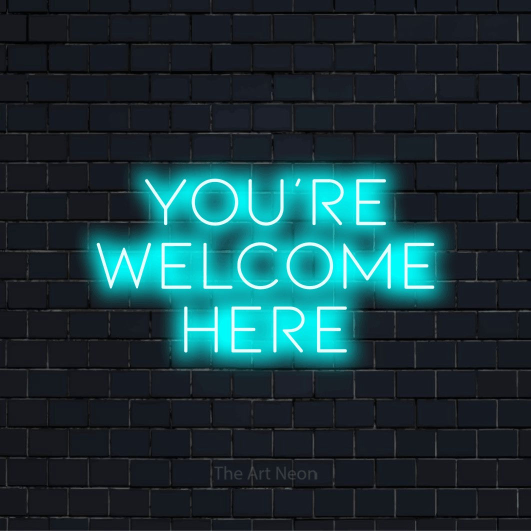 "You’re Welcome Here" text design with neon effect on a black brick wall